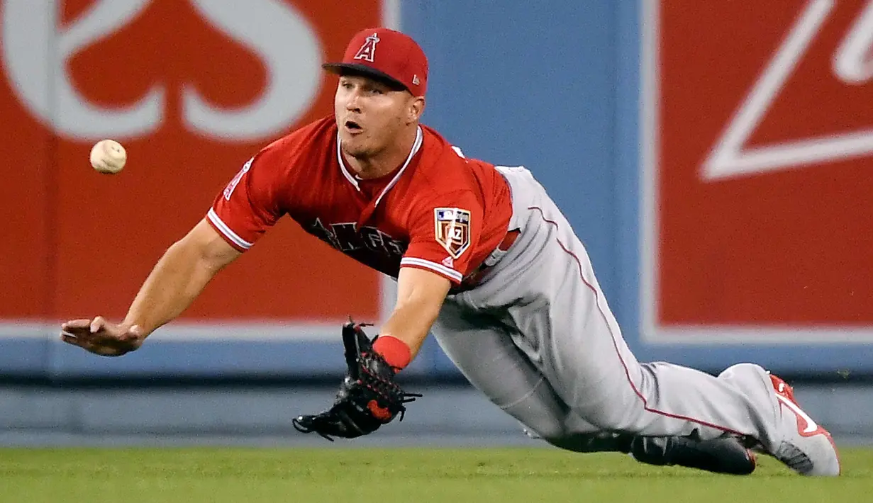 Pemain Los Angeles Angels, Mike Trout berusaha menangkap bola pukulan pemain Los Angeles Dodgers, Chris Taylor selama inning pertama pertandingan bisbol pramusim di Los Angeles (26/3). (AP Photo/Mark J. Terrill)