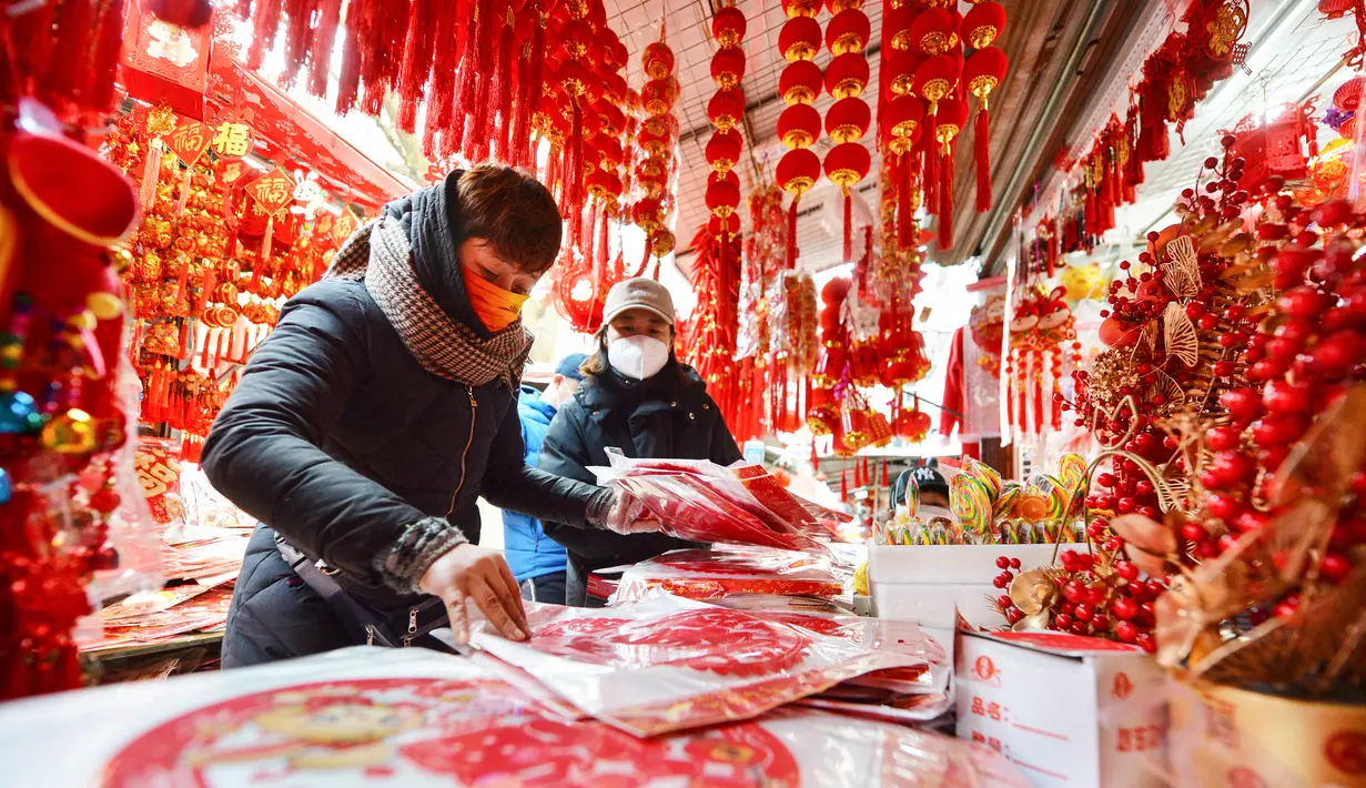Orang-orang membeli pernak-pernik dekorasi menjelang Hari Tahun Baru di sebuah pasar di Qingdao, di provinsi Shandong timur China pada 25 Desember 2022. Warga China mulai berburu pernak-pernik Tahun Baru seperti lampion, kartu tahun baru, baju, dan hiasan rumah. (AFP/China Out)