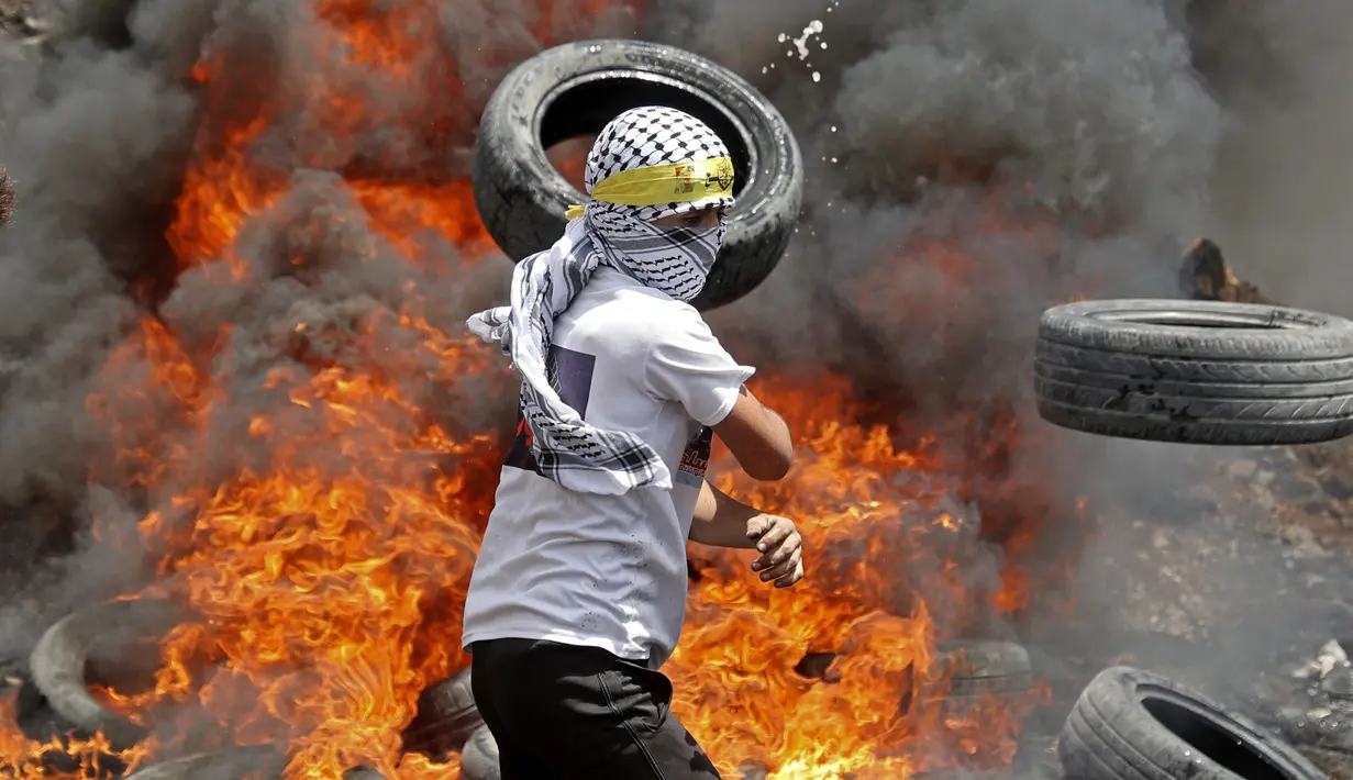 <p>Pengunjuk rasa Palestina membakar ban di tengah bentrokan dengan pasukan keamanan Israel menyusul demonstrasi menentang perampasan tanah oleh Israel di Desa Kfar Qaddum dekat pemukiman Yahudi Kedumim, Tepi Barat, 6 Mei 2022. (JAAFAR ASHTIYEH/AFP)</p>