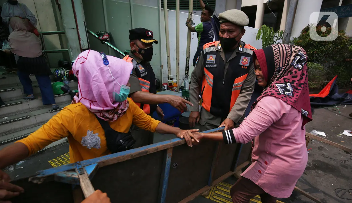 Pedagang kaki lima (PKL) berebut meja dengan petugas Satpol PP yang melakukan penertiban di trotoar Pasar Tanah Abang, Jakarta, Senin (4/10/2021). Penertiban dilakukan untuk memberikan kenyamanan dan keamanan bagi para pengguna jalan yang melintas di trotoar tersebut. (Liputan6.com/Angga Yuniar)