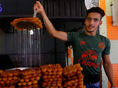 Seorang pria menjajakan kue manis khas Aljazair jelang Ramadan, di Aljir, Jumat (26/5). Kue-kue dengan rasa manis umum ditemukan sebagai menu untuk berbuka puasa. (AP Photo / Anis Belghoul)