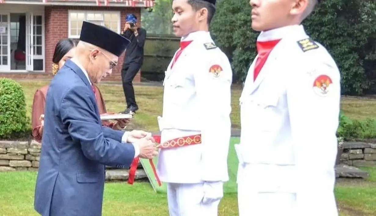 Reiki alias Eki, putra Ratna Listy disempatkan sebuah kain di pinggangnya oleh Desra Percaya, Duta Besar RI di London jelang upacara. (Foto: Instagram/@ratna_listy)