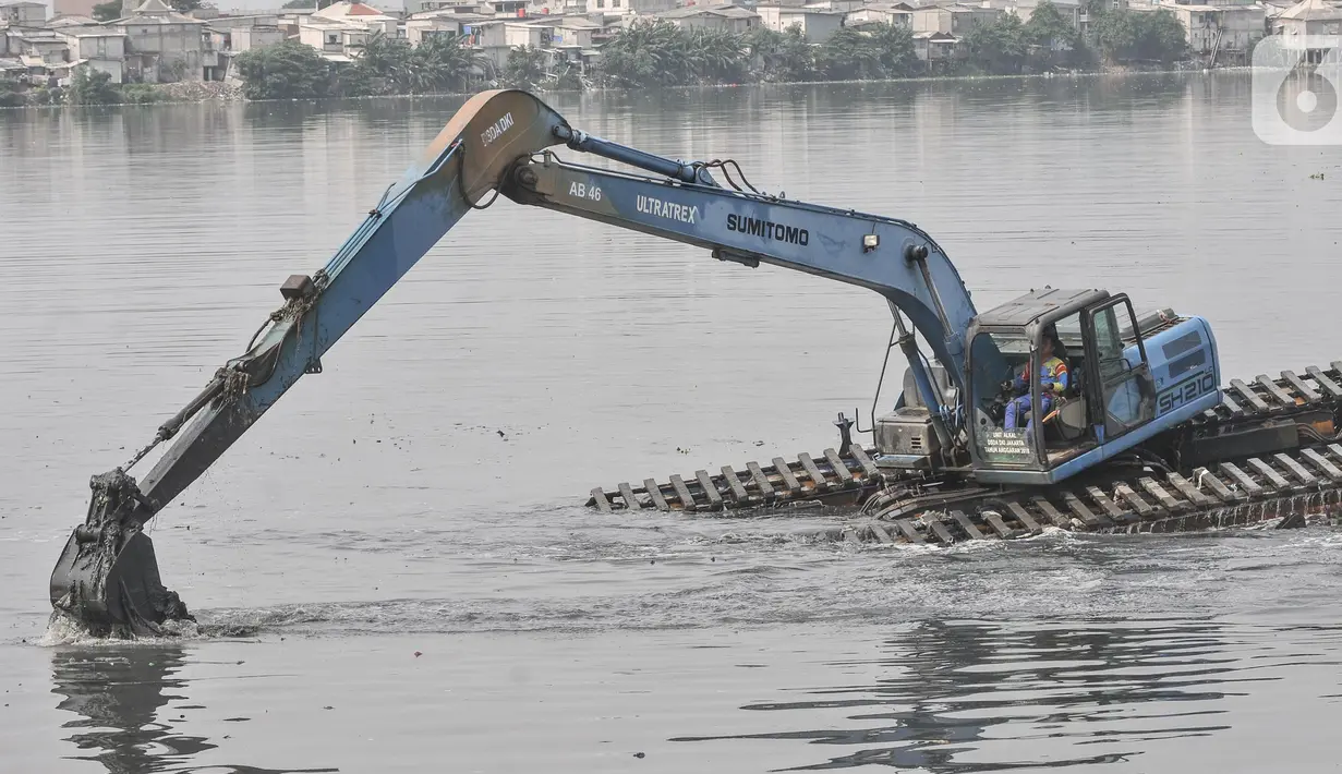 Pekerja menggunakan beko mengeruk lumpur yang mengendap di Waduk Pluit, Senin (13/6/2022). Pengerukan lumpur rutin ini dilakukan sebagai upaya mengurangi endapan serta tanaman liar dan mencegah banjir di kawasan tersebut. (merdeka.com/Iqbal S Nugroho)