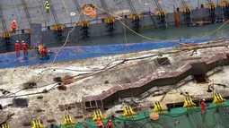 Pekerja mempersiapkan diri mengangkat bangkai kapal feri Sewol di pulau barat daya Jindo, Korea Selatan, Kamis (23/3). Operasi pengangkatan feri sewol menjadi tuntutan utama keluarga 9 korban yang masih dinyatakan hilang. (Park Gyung-woo/Hankookilbo/AP)