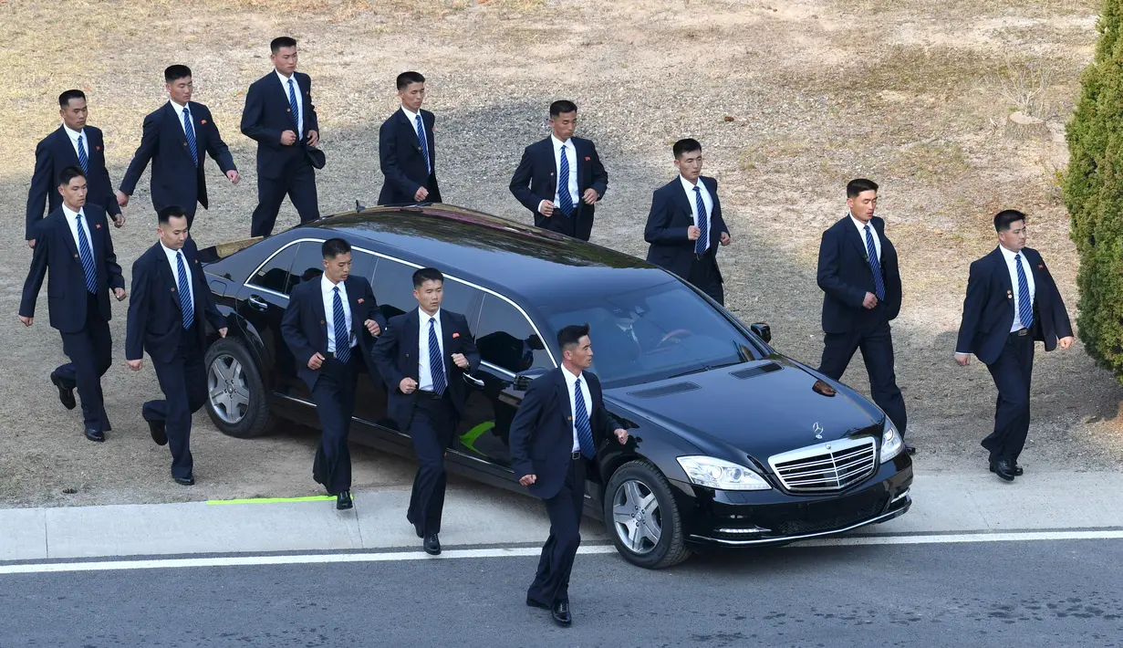 Pengawal berlari di samping mobil yang membawa Pemimpin Korea Utara Kim Jong-un saat akan menanam pinus dengan Presiden Korea Selatan Moon Jae-in dalam KTT Korsel-Korut di zona demiliterisasi, Panmunjom, Korsel, Jumat (27/4). (Korea Summit Press Pool/AP)