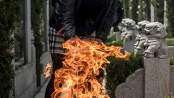 Seorang wanita membakar dupa sebagai persembahan selama festival Qingming di sebuah pemakaman di Shanghai (6/6). Ritual ini umumnya dirayakan pada tanggal 5 April atau 4 April pada tahun kabisat. (AFP/Johannes Eisele)