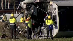 Petugas menyelidiki sebuah kereta yang tergelincir sesaat setelah menabrak crane (derek) di Dalfsen, Belanda, Selasa (23/2). Kecelakaan itu menewaskan sang masinis dan melukai empat pengemudi mobil yang berada di dekat lokasi kejadian. (REUTERS/NOS)