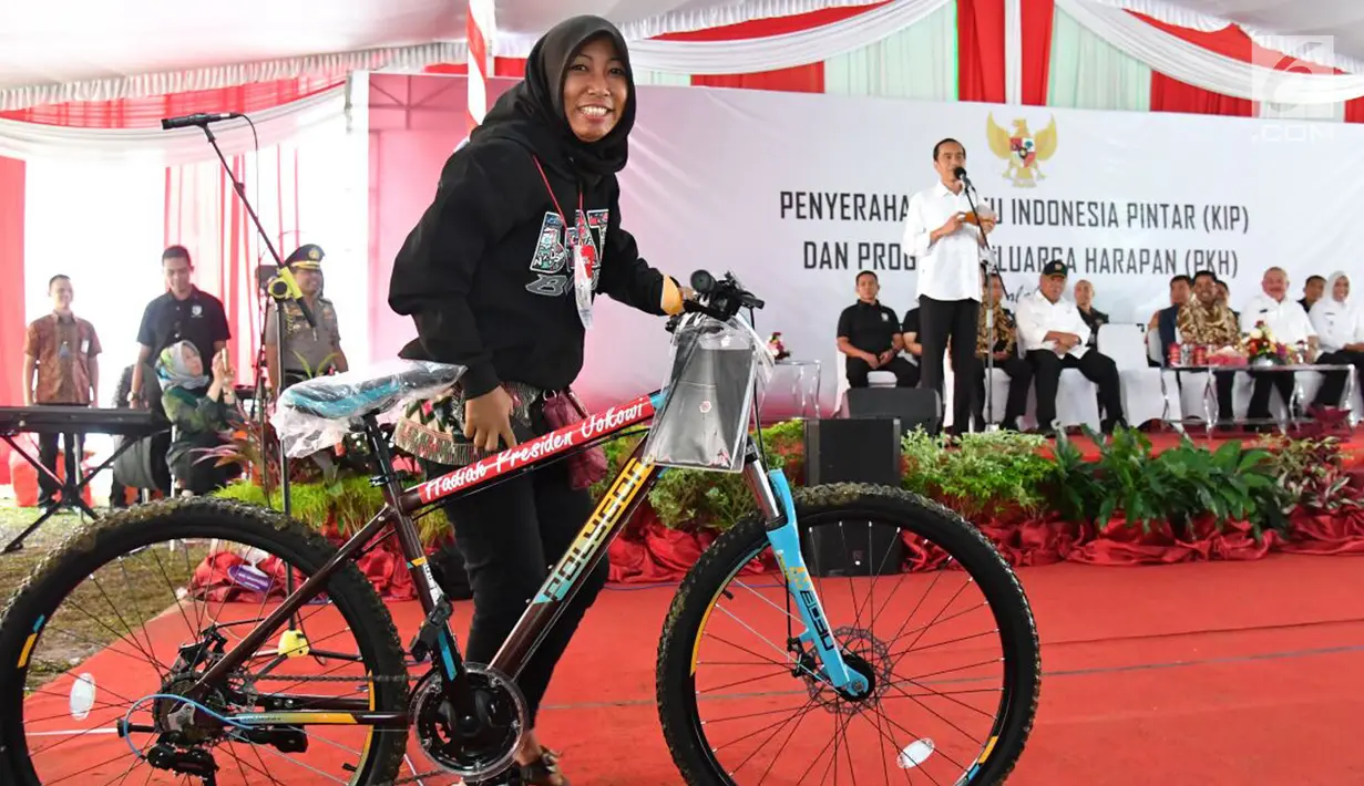 Seorang wanita menerima hadiah sepeda usai menjawab pertanyaan Presiden Jokowi dalam acara penyerahan KIP dan PKH di SMA Negeri 1 Palembang, Sumatra Selatan (22/1). (Liputan6.com/Pool/Biro Setpres)