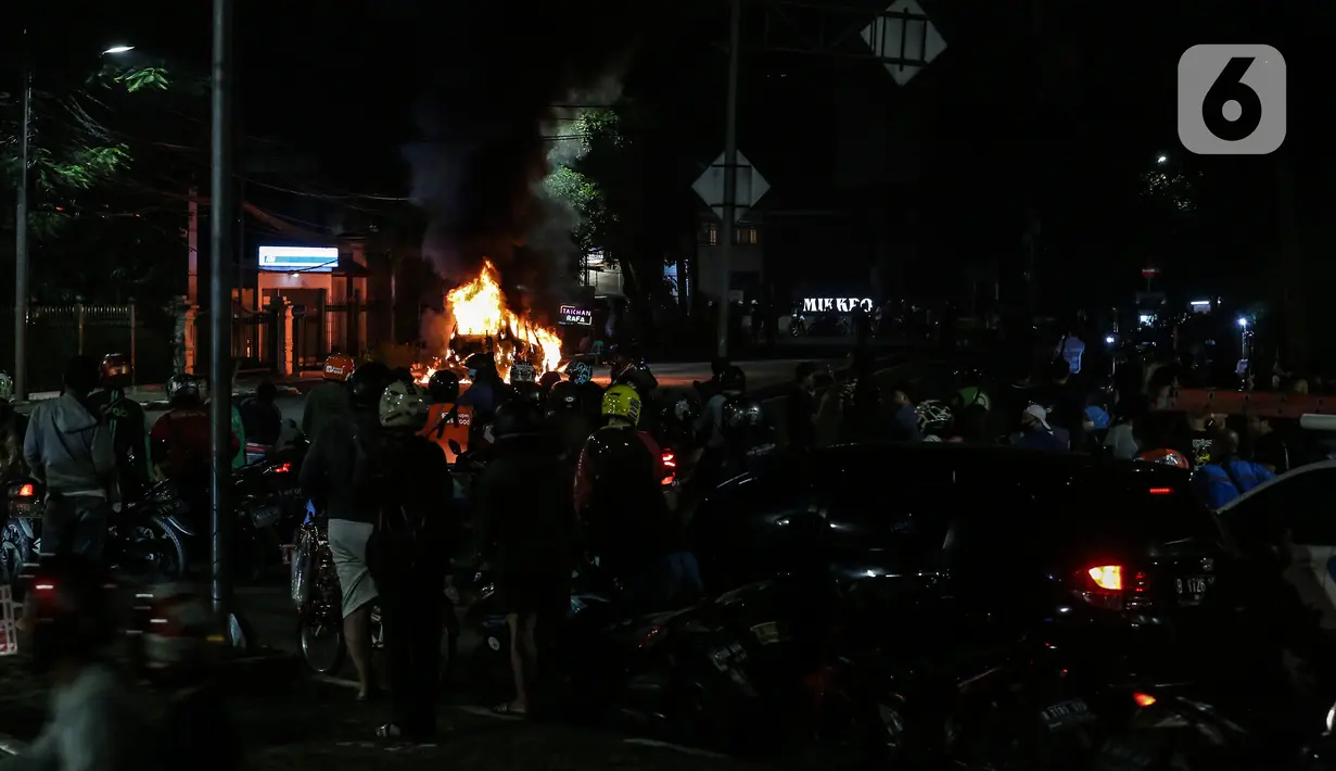 Warga menyaksikan sebuah mobil terbakar di Jalan Asia Afrika, Jakarta, Kamis (18/3/2021) dinihari.  Kobaran api yang melahap mbil jenis minibus bernomor polisi B 1608 SGZ itu menjadi tontonan warga. (Liputan6.com/Johan Tallo)