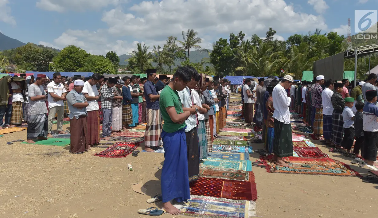 Umat muslim salat Jumat di sebuah ladang di dekat tempat penampungan sementara setelah gempa di Pemenang, Lombok (10/8). Menurut menteri senior, korban tewas akibat gempa dahsyat 6,9 SR di pulau Lombok melonjak di atas 300 orang. (AFP Photo/Adek Berry)