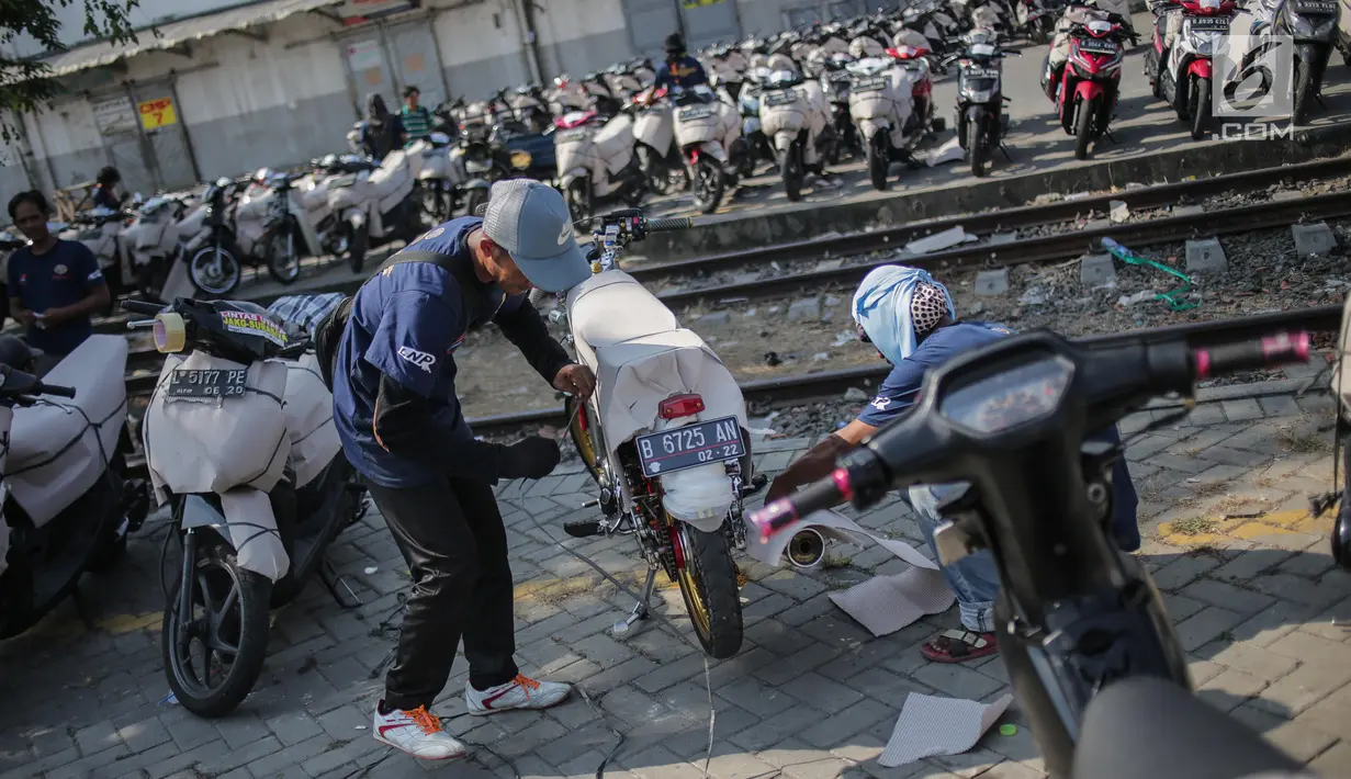 Pekerja membungkus motor pemudik sebelum dikirim dengan kereta api di Stasiun Jakarta Gudang, Selasa (28/5/2019). Direktorat Lalu Lintas dan Angkutan Kereta Api Kementerian Perhubungan mengangkut 18.096 motor pemudik secara gratis pada mudik Lebaran 2019. (Liputan6.com/Faizal Fanani)