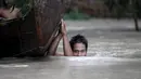 Seorang pria berjalan melintasi banjir setinggi mulut sambil membawa perahu di Zalun Township, Irrawaddy Delta, Myanmar (6/8/2015). Meningkatnya volume luapan sungai sudah membahayakan warga sekitar di desa tersebut. (REUTERS/Soe Zeya Tun)