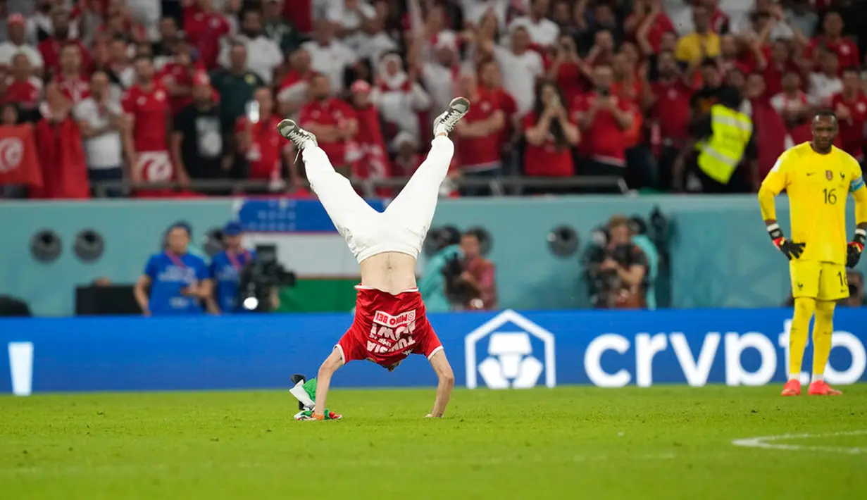 Seorang penyusup melakukan salto saat memasuki lapangan pada pertandingan sepak bola Grup D Piala Dunia 2022 antara Tunisia dan Prancis di Education City Stadium, Al Rayyan, Qatar, 30 November 2022. Seorang pria yang memakai jersey Tunisia bernomor 8 dan membawa bendera Palestina berlari memasuki lapangan. (AP Photo/Christophe Ena)