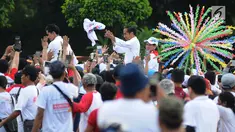 Capres 01 Joko Widodo didampingi Iriana Jokowi dan Kaesang Pangarep melempar kaus seusai 'Konser Putih Bersatu' di Stadion GBK, Jakarta, Sabtu (13/4). Pasangan Capres dan Cawapres 01 menggunakan kereta kencana seusai Konser Putih Bersatu menuju lokasi debat. (Liputan6.com/Herman Zakharia)