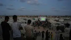 Warga Palestina menyaksikan siaran langsung pertandingan sepak bola Piala Dunia antara Spanyol dan Arab Saudi melalui layer lebar di Nuseirat, Jalur Gaza Tengah, Minggu 21 Juni 2026. (AP Photo/Abdel Kareem Hana)