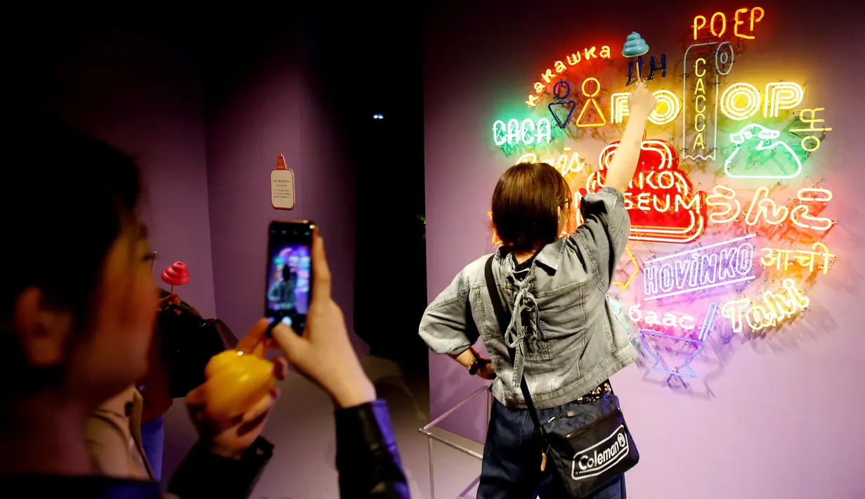 Seorang pengunjung berpose di depan tulisan toilet dalam berbagai bahasa di Museum Unko di Yokohama, Jepang pada Rabu (17/4). Untuk masuk ke dalam museum seni ini, traveler harus membayar tiket 1.600 Yen (Rp 205 ribu) untuk dewasa, dan 900 Yen (Rp 115 ribu) untuk anak-anak. (REUTERS/Kim Kyung-hoon)