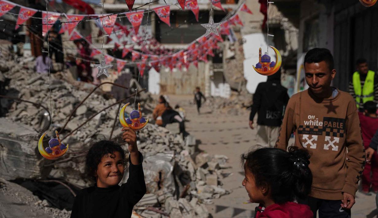 Warga Palestina menggantungkan hiasan Ramadan di samping reruntuhan rumah yang hancur di Khan Younis, Jalur Gaza selatan, Minggu 15 Februari 2026. Suasana jelang bulan suci Ramadan di Gaza pada tahun 2026 atau 1447 Hijriah berlangsung dalam suasana yang memprihatinkan. (AP Photo/Abdel Kareem Hana)