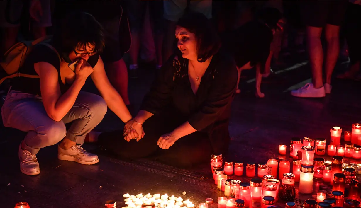Dua wanita menangis saat memperingati gadis berusia 15 tahun Alexandra yang terbunuh di depan Kementerian Dalam Negeri Rumania di Bucharest (27/7/2019). Alexandra telah dibunuh setelah ia menelepon polisi tiga kali untuk melaporkan penculikannya dirinya.  (AFP Photo/Daniel Mihailescu)