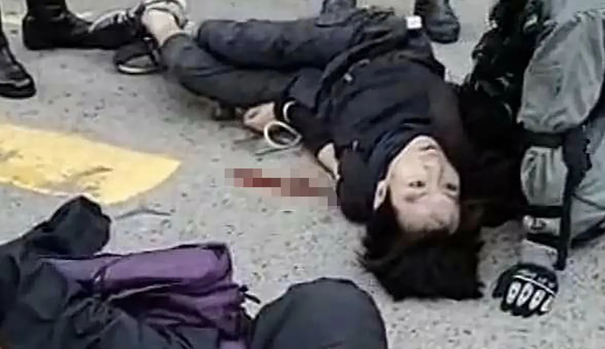 Demonstran prodemokrasi terbaring setelah ditembak oleh seorang polisi saat terjadi protes di Distrik Sai Wan Ho, Hong Kong, Senin (11/11/2019). Hingga kini belum diketahui kondisi demonstran yang ditembak oleh polisi tersebut. (STRINGER/CUPID NEWS/AFP)