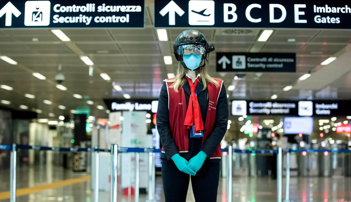 Seorang petugas mengenakan pemindai 'helm pintar' untuk mengukur suhu tubuh penumpang di bandara internasional Leonardo da Vinci, Roma, Italia pada 6 Mei 2020. Hal ini dilakukan guna menyaring orang yang memiliki gejala infeksi virus corona. (Roberto Monaldo/LaPresse via AP)