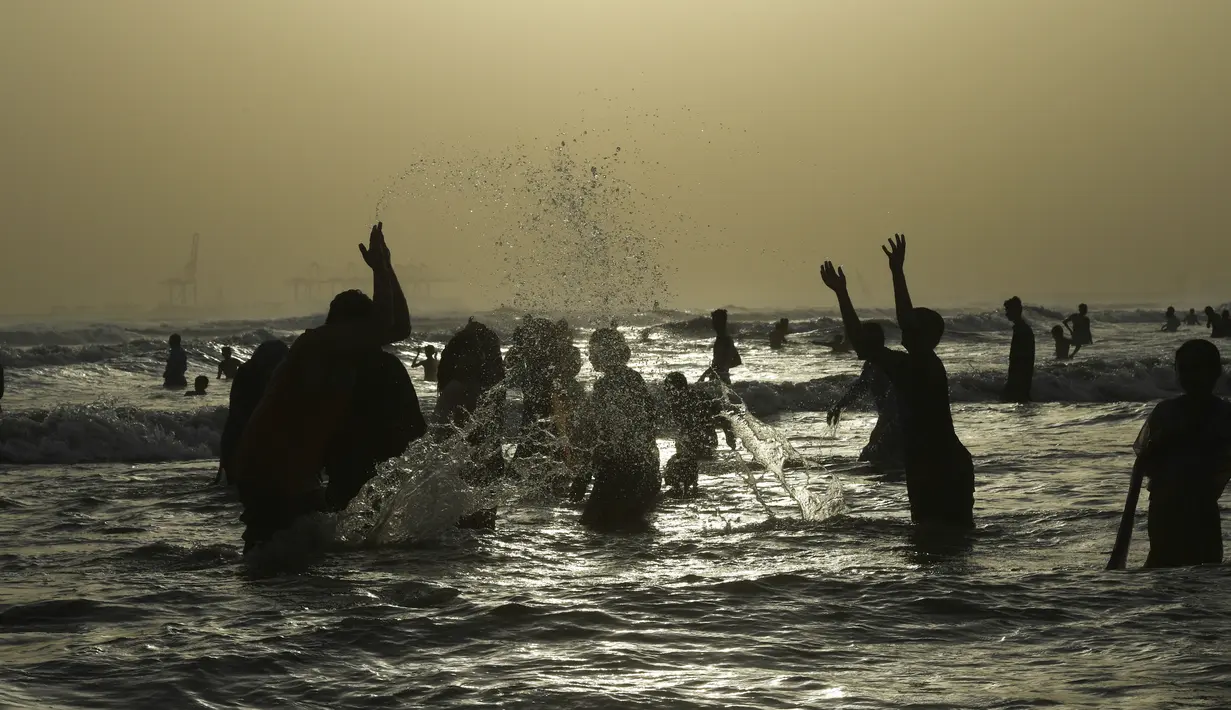 Para pemuda bermain air saat mendinginkan tubuhnya di laut selama musim panas di Karachi, Pakistan (14/6/2019). Memasuki musim panas, warga Pakistan ramai-ramai mendinginkan tubuhnya di laut. (AFP Photo/Asif Hassan)
