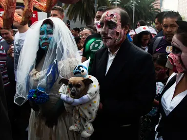 Beberapa orang berjalan selama Zombie Walk di Mexico City, Minggu (11/11). Ratusan orang dengan penampilan yang seram serta mengenakan pakaian compang-camping berkumpul di pusat bersejarah ibu kota Meksiko dalam acara tahunan tersebut. (AP/Claudio Cruz)