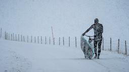 Seorang peselancar membawa papan selancar dengan sepeda menuju pantai di Lofoten Islands, Norwegia, (11/3/2018). Suhu udara minus 13°C dan suhu diatas air sekitar 4°C. (AFP/Oliver Morin)