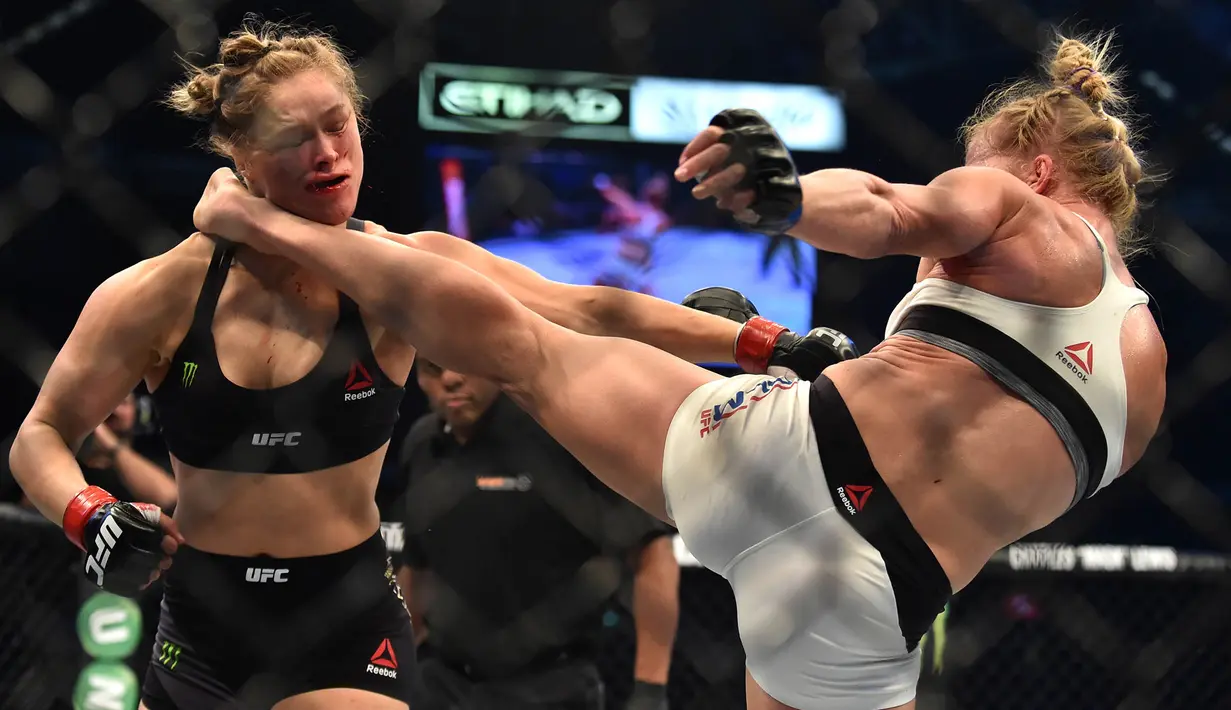 Tendangan dari Holly Holm, mendarat di kepala Ronda Rousey, perebutan gelar juara kelas bantam UFC Women di Stadion Etihad, Melbourne, Minggu (15/11/2015). Rousey, kalah KO dari Holm. (AFP Photo/Paul Crock)