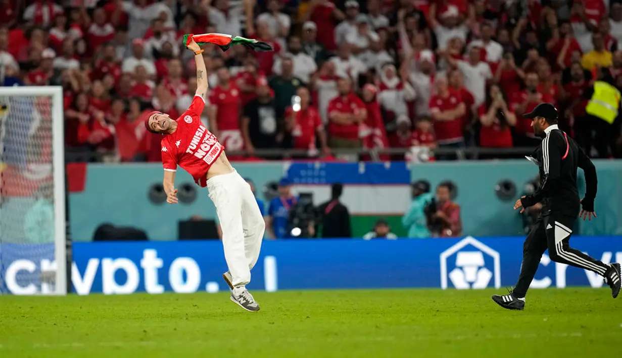 Seorang penyusup melakukan salto saat memasuki lapangan pada pertandingan sepak bola Grup D Piala Dunia 2022 antara Tunisia dan Prancis di Education City Stadium, Al Rayyan, Qatar, 30 November 2022. Saat diselidiki, pria yang melakukan aksi tersebut diketahui bernama Mino Bei, seorang Youtuber dengan akun @epicmino8964. AP Photo/Christophe Ena)