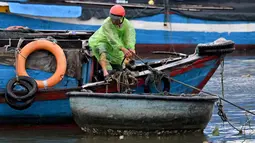 Badan Meteorologi Nasional Vietnam memperkirakan, Topan Kalmaegi akan disertai gelombang setinggi delapan meter atau 26 kaki dan badai yang kuat. Tampak dalam foto, seorang pria mengikat perahu untuk melindunginya dari dampak Topan Kalmaegi di Pelabuhan Perikanan Quy Nhon, Provinsi Gia Lai, Vietnam Tengah, pada 6 November 2025. (Nhac NGUYEN/AFP)
