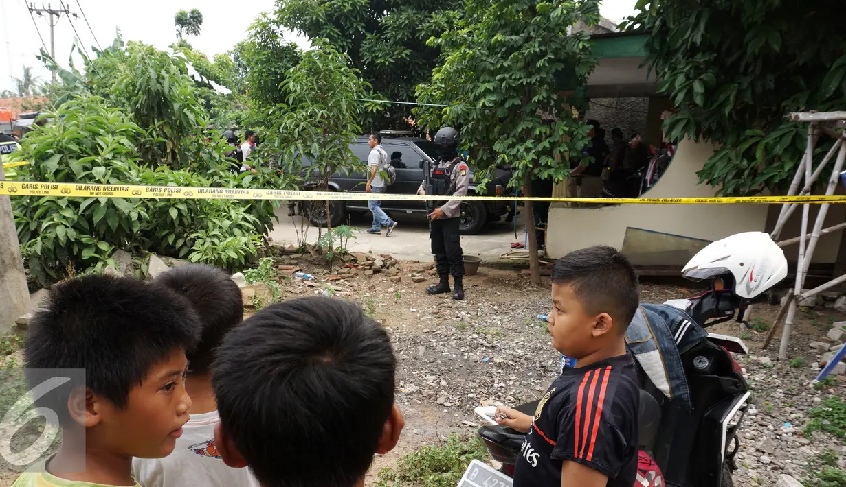 Anggota polisi bersenjata lengkap bersiaga di depan rumah orangtua SA, pelaku penusukan tiga anggota polisi, di Kelurahan Sepatan, Tangerang, Kamis (20/10). Sebelumnya SA menyerang Pospol Cikokol dan melukai tiga anggota polisi. (Liputan6.com/Stringer)