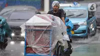 Pedagang menutupi gerobaknya dengan plastik saat hujan deras di kawasan Thamrin, Jakarta, Rabu (23/11/2022). Sejak Oktober, DKI Jakarta mulai memasuki musim penghujan yang sudah masuk ke dalam tahap ekstrem. (Liputan6.com/Faizal Fanani)