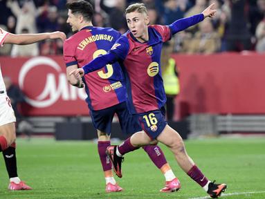 Pemain Barcelona, Fermin Lopez melakukan selebrasi setelah mencetak gol kedua timnya ke gawang Sevilla dalam laga lanjutan Liga Spanyol 2024/2025 di Ramon Sanchez Pizjuan Stadium, Sevilla, Spanyol, Senin (10/02/2025) dini hari WIB. (AFP/Cristina Quicler)