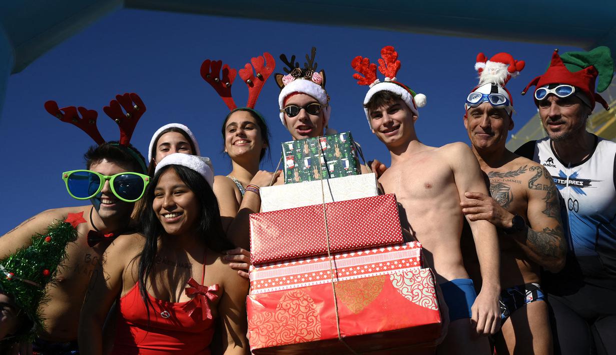Para peserta mengenakan kostum bernuansa natal seperti topi Santa Klaus dan topi tanduk rusa saat mengikuti tradisi lomba renang unik saat natal di pelabuhan tua Barcelona (Port Vell Barcelona), Spanyol, Senin (25/12/2023) waktu setempat. Lomba tersebut dimenangkan oleh Edward Poeschke dengan mencatatkan waktu 3 menit 17 detik. (AFP/Josep Lago)