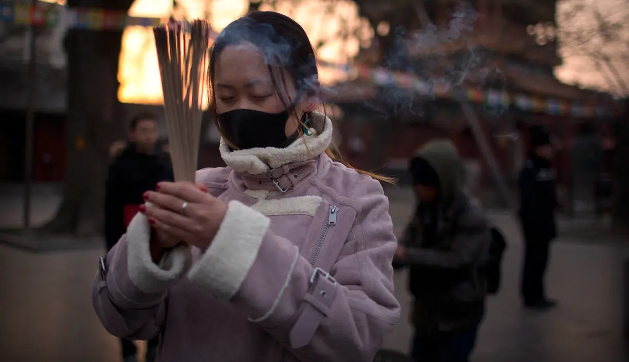 Seorang wanita memegang dupa berdoa di Kuil Lama di Beijing (5/2). Orang-orang China merayakan hari pertama Tahun Baru Imlek pada hari Selasa, Tahun Babi di zodiak Tiongkok dengan berdoa di kuil. (AP Photo/Mark Schiefelbein)