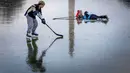 Monumen Washington terlihat dalam pantulan saat kakak beradik Jacek Zavora (21) dan Zach Zavora (10) bermain hoki di Reflecting Pool yang membeku, National Mall, Washington, Amerika Serikat, 26 Desember 2022. Meski tidak diizinkan, banyak warga yang bermain dengan sepatu roda dan meluncur di antara monumen. (AP Photo/Andrew Harnik)