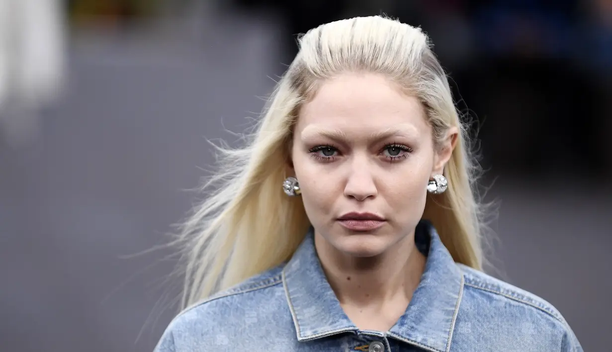 Gigi Hadid mengenakan kreasi untuk koleksi busana ready-to-wear Spring/Summer 2023 dari Givenchy yang dipresentasikan selama Paris Fashion Week di Paris pada Minggu, 2 Oktober 2022. Rambut pirang cerah milik Gigi ditata dengan cara yang sama dengan milik Bella saat ia menambahkan sepasang anting perak kecil tapi tebal. (AFP/Julien De Rosa)