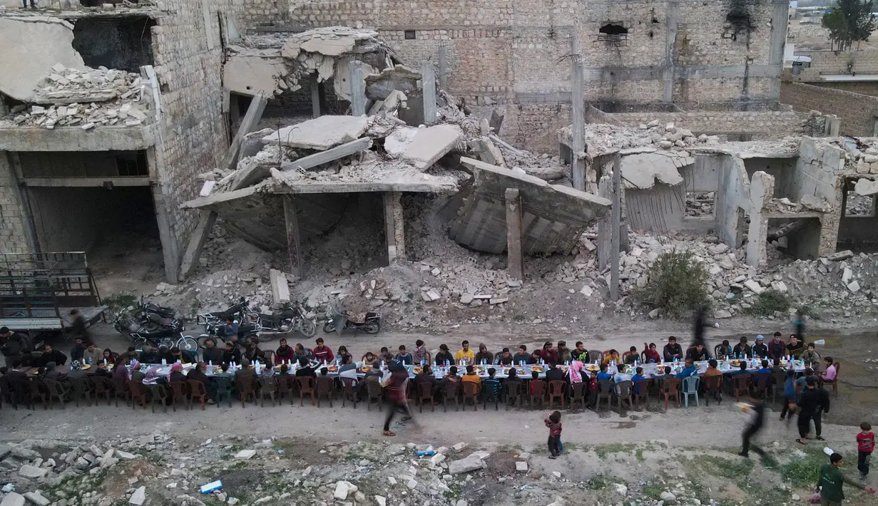 Pemandangan udara menunjukkan warga Suriah duduk di tengah-tengah bangunan yang rusak untuk berbuka puasa di Tadef, dekat kota perbatasan al-Bab, yang dikendalikan oleh pemberontak yang didukung Turki di Suriah di pedesaan timur provinsi Aleppo (18/4/2022). (AFP/Bakr Alkasem)