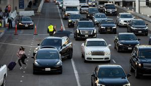 Seorang wanita bergegas ke terminal setelah diturunkan di Bandara Internasional Los Angeles, Los Angeles, Amerika Serikat, 19 Desember 2022. Liburan Natal dan Tahun Baru bagi sebagian warga Amerika Serikat dan Eropa tahun ini menghadirkan kekhawatiran karena tekanan ekonomi. (AP Photo/Jae C. Hong)