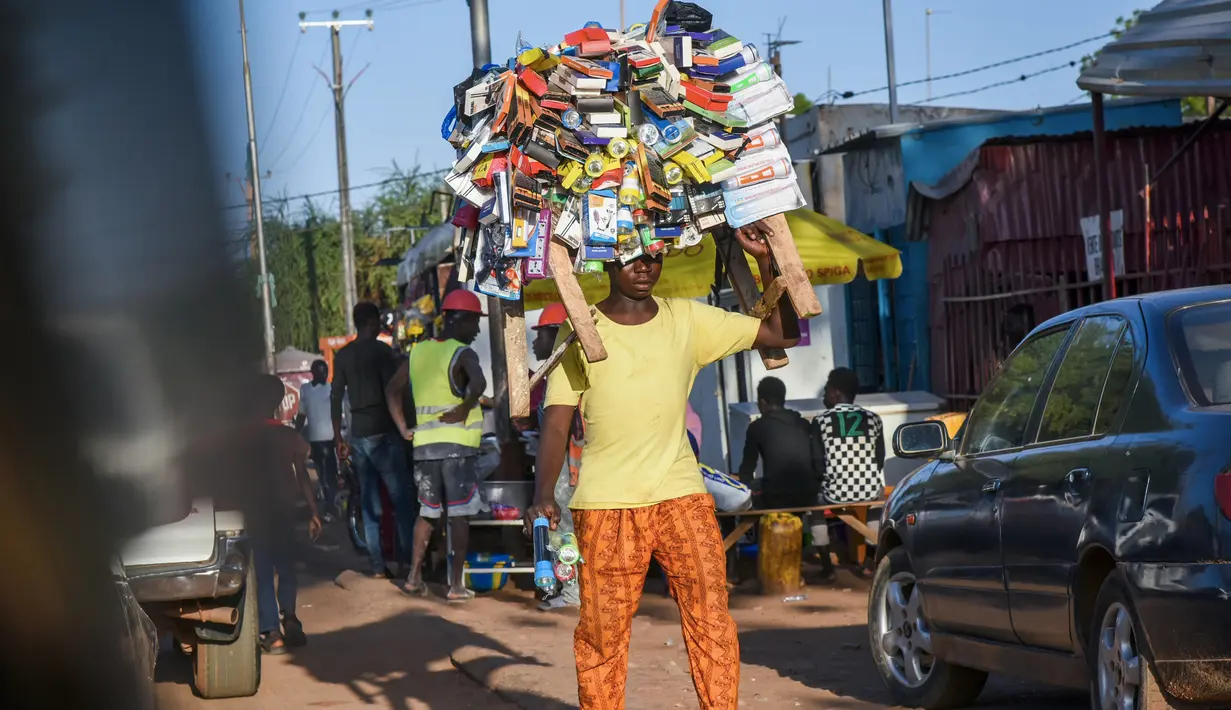 Seorang pedagang kaki lima membawa barang dagangannya di jalan Niamey, Niger (10/7/2019). Nama negara ini diambil dari Sungai Niger. Ibu kotanya ialah Niamey. Niger adalah negara berkembang, dan merupakan negara dengan urutan ke-188 Indeks Pembangunan Manusia PBB. (AFP Photo/Issouf Sanogo)