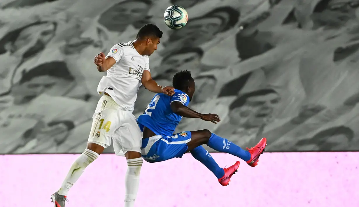 Gelandang Real Madrid,  Casemiro berebut bola udara dengan bek Getafe, Djene pada pertandingan lanjutan La Liga Spanyol di stadion Alfredo di Stefano di Valdebebas, Madrid (2/7/2020). Madrid menang tipis atas Getafe 1-0.  (AFP Photo/Gabriel Bouys)