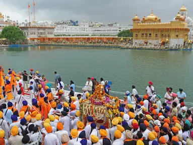 Umat Sikh membawa teks pokok agama Sikhisme, Palki Guru Granth Sahib selama prosesi keagamaan dari Gurudwara Ramsar ke Akal Takht Sahib di Kuil Emas, Amritsar, India, Rabu (19/8/2020). Acara ini untuk memperingati 416 tahun pelantikan Guru Granth Sahib. (NARINDER NANU/AFP)