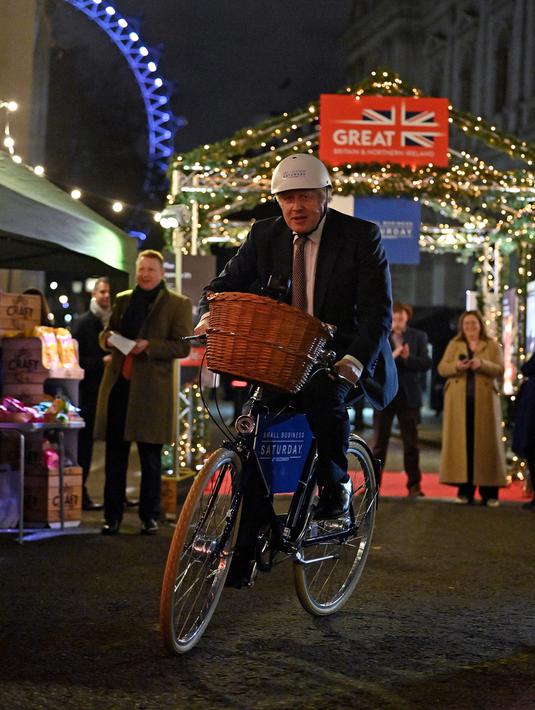 Perdana Menteri Inggris Boris Johnson mengendarai sepeda saat kunjungannya ke pasar Makanan dan Minuman Inggris yang didirikan di Downing Street, London, 30 November 2021. Sebanyak 12 bisnis dari seluruh Inggris memiliki kios untuk memamerkan produk mereka. (JUSTIN TALLIS/AFP/POOL)
