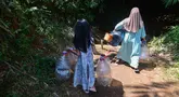 Seorang anak menemani ibunya Warga mengambir air dari satu-satunya sumber mata air di di Kampung Cijaura, Desa Cidokom, Bogor, Jawa Barat, Minggu (26/07/2026). (KLY/ Arie Basuki)