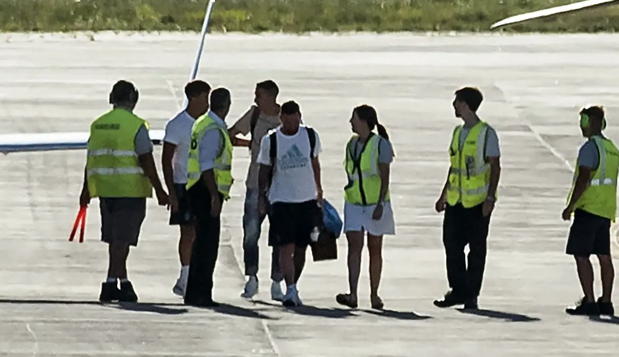 Pemain Argentina, Lionel Messi (kanan) dan Angel Di Maria terlihat berjalan memasuki helikopter saat parade kemenangan Piala Dunia 2022 di provinsi Buenos Aires, pada 20 Desember 2022. Messi dan kolega terpaksa dievakuasi karena bus yang mereka gunakan tak bisa mencapai lokasi yang direncanakan akibat membeludaknya warga di jalanan. (AFP/Matias Baglietto)