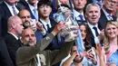 Selebrasi pelatih Manchester City, Pep Guardiola dengan trofi Piala FA 2022/2023 setelah mengalahkan Manchester United 2-1 pada laga final di Wembley Stadium, London (3/6/2023). (AFP/Glyn Kirk)