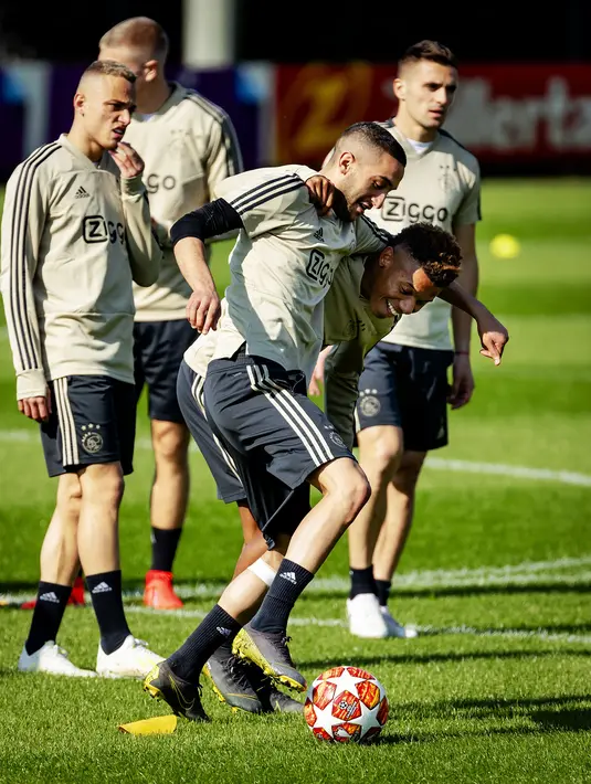 Pemain Ajax Amsterdam, Hakim Ziyech berebut bola dengan David Neres saat sesi latihan di Sports park De Toekomst, Belanda (9/4). Ajax akan bertanding melawan wakil Italia Juventus pada leg pertama babak perempatfinal Liga Champions di Johan Cruyff Arena. (AFP Photo/ANP/Robin van Lonkhuijsen)