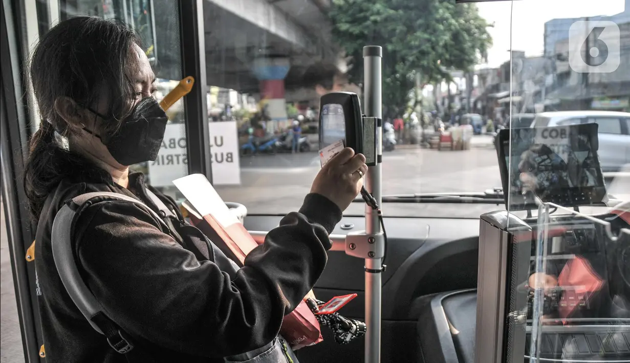 Penumpang memindai kartu sebelum menaiki bus listrik Transjakarta rute Kampung Melayu-Tanah Abang via Cikini (5M) saat uji coba di Terminal Kampung Melayu, Jakarta Timur, Selasa (26/7/2022). PT Transjakarta mengubah rute uji coba bus listrik yang sebelumnya jurusan Kampung Melayu-Tanah Abang (5F) agar masyarakat dapat menjajal secara merata sekaligus memperkenalkan jalur bus yang melayani mulai pukul 05.00-21.00 WIB. (merdeka.com/Iqbal S Nugroho)