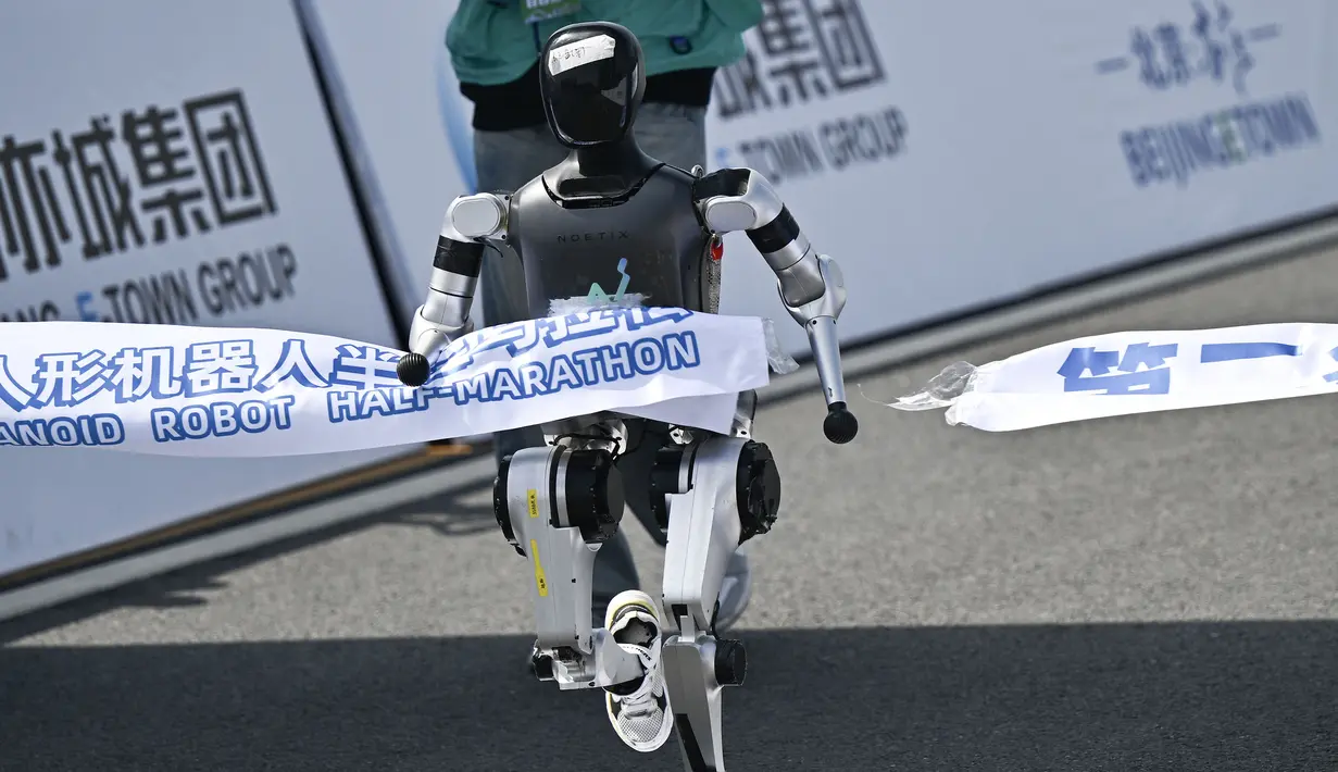 Sebuah robot humanoid melewati garis finis dalam ajang lari half marathon yang berlangsung di Beijing, China, Sabtu (19/04/2025). (AFP/Pedro Pardo)