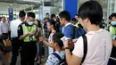 Petugas keamanan memeriksa informasi penerbangan para pelancong di gerbang pintu masuk utama bandara di Hong Kong, Rabu (14/8/2019). Bandara Hong Kong kembali membuka penerbangan keberangkatan pada Rabu pagi setelah sempat lumpuh selama dua hari terakhir akibat demonstrasi. (AP/Vincent Thian)
